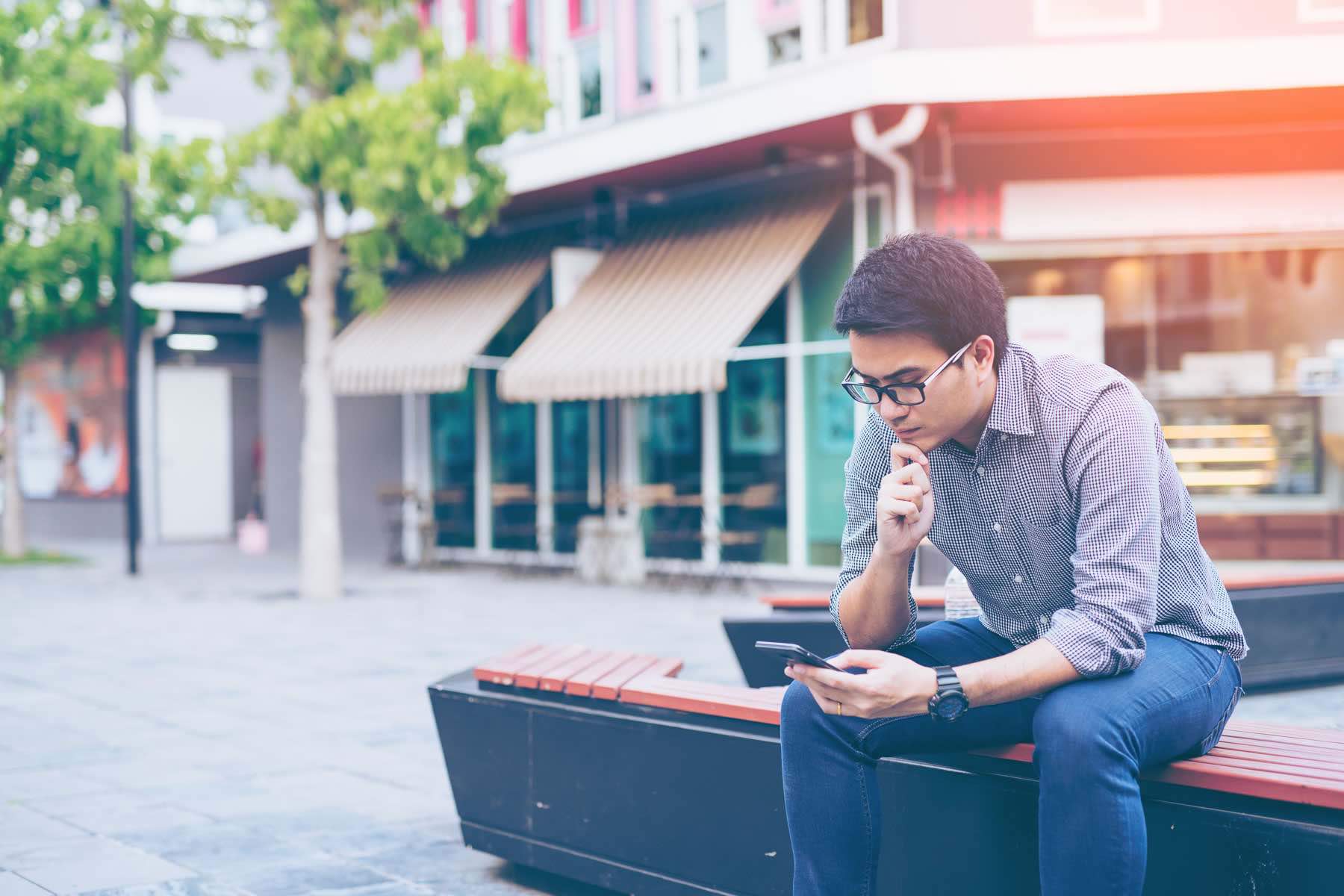 Young asian handsome businessman concentrated while reading his smartphone. Portrait of asian business man reading message with smart phone in outdoor.